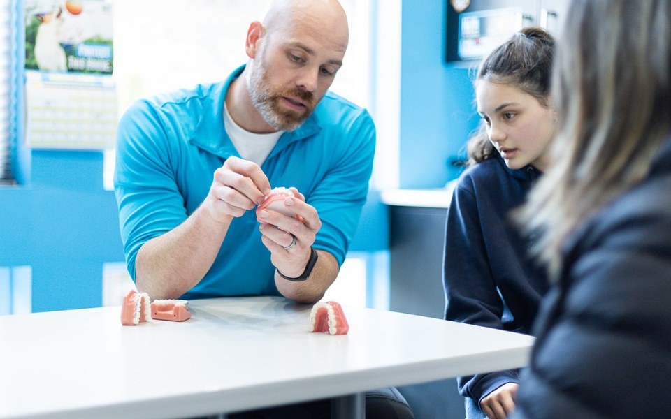 Dr. Williams showing a braces model to a young patient during a consultation