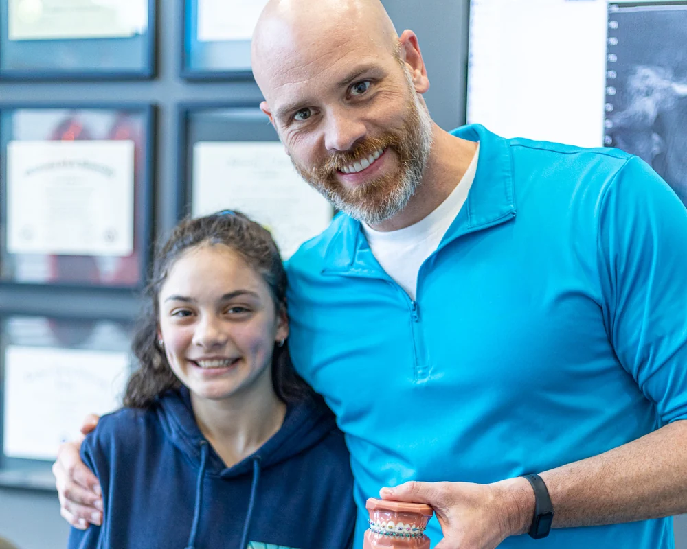 Dr. Aaron Williams with a young patient, holding a model of teeth with braces
