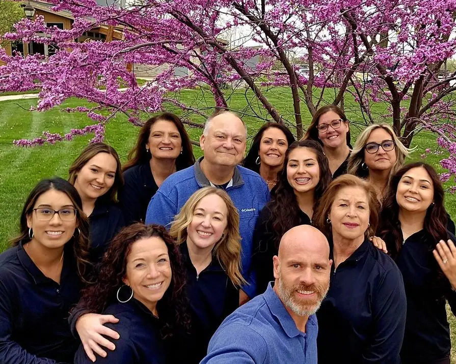 The Siouxland Orthodontics team together outside the office under a flowering tree